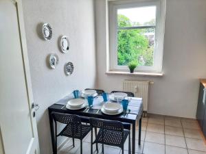 a black table with chairs and plates and a window at Cozy 1 room apartment in Magdeburg in Magdeburg