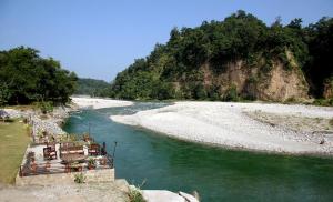 a boat traveling down a river next to a mountain at Riverside By Aahma in Garjia