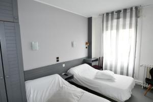 two beds in a room with a window at Le Pasteur in Brest