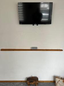 a flat screen tv hanging on a wall with a wooden stick at Domek KALINKA -Góry Sowie-Rzeczka in Rzeczka