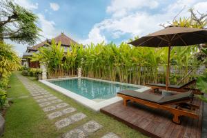 a swimming pool with an umbrella and a bench at BUBU CANGGU Guesthouse in Canggu