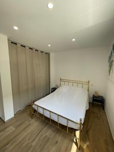 um quarto com uma cama com lençóis brancos e pisos em madeira em Carry le Rouet : superbe T2 neuf em Carry-le-Rouet