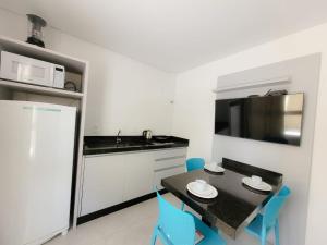 a kitchen with a black table and blue chairs at Hospeda Mariscal Flat in Bombinhas