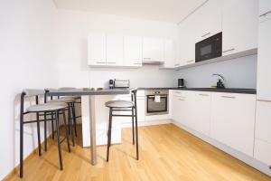 een keuken met witte kasten en barkrukken bij Exclusive 2-Bedroom condo with Pool & Balcony in Wenen