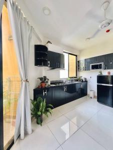 eine Küche mit schwarzen Schränken und einem großen Fenster in der Unterkunft BODU ASHI MALDIVES - Central 3 Bedroom Apartment in Hulhumale