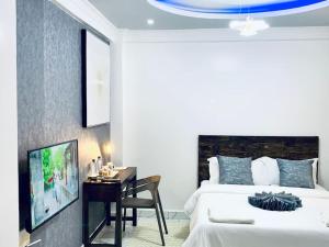 Dormitorio con cama, escritorio y TV en Arabel Studio Apartment, en Nanyuki