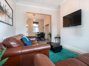 a living room with a leather couch and a flat screen tv at Pass the Keys Beautiful 4BR Restored Red Brick Cafes and Park in Belfast