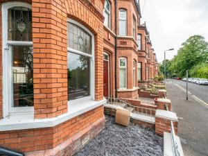 a brick building with two windows on a street at Pass the Keys Beautiful 4BR Restored Red Brick Cafes and Park in Belfast