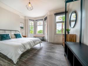 a bedroom with a bed and a dresser and windows at Pass the Keys Beautiful 4BR Restored Red Brick Cafes and Park in Belfast