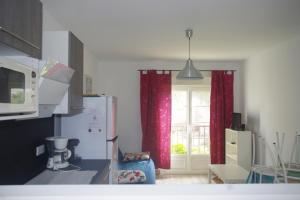 a kitchen with a refrigerator and a window with red curtains at Villa Nausicaa in Hyères