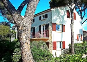 a white house with red doors and a tree at Villa Nausicaa in Hyères