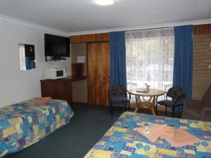 Cette chambre comprend 2 lits et une table. dans l'établissement Wintersun Motel, à Victor Harbor