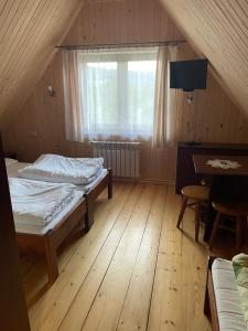een slaapkamer met 2 bedden, een tafel en een raam bij Felągówka in Murzasichle