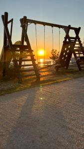 a swing set with the sunset in the background at Apartmani Sirius in Silba