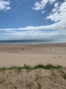a beach with people walking on the sand at Phoenix caravan hire, Trecco bay in Porthcawl