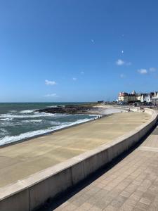 a sidewalk next to a beach with the ocean at Phoenix caravan hire, Trecco bay in Porthcawl
