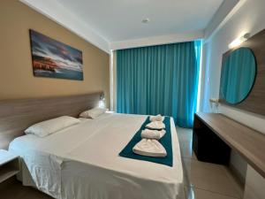 a bedroom with a large white bed and a mirror at Sunny Blue Hotel in Ayia Napa