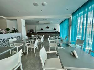 a dining room with tables and white chairs at Sunny Blue Hotel in Ayia Napa