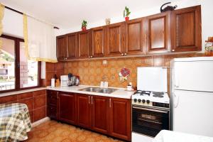 a kitchen with wooden cabinets and a sink and a refrigerator at Apartments by the sea Grscica, Korcula - 129 in Prizba