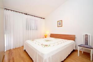 a white bedroom with a bed and a chair at Apartments by the sea Prizba, Korcula - 149 in Prizba