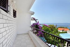 d'un balcon avec des fleurs violettes et une vue sur l'océan. dans l'établissement Apartments by the sea Prizba, Korcula - 149, à Prižba
