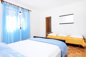 a bedroom with two beds and a window with blue curtains at Apartment Brna 147a in Smokvica