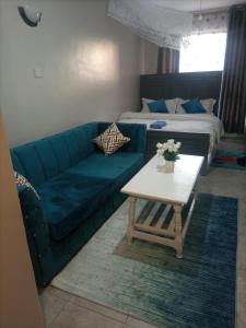 a living room with a couch and a table and a bed at Pazoori Furnished Studios and 1 bedrooms in Nairobi