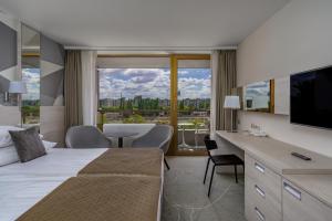 a hotel room with a bed and a large window at Ensana Thermal Margaret Island in Budapest