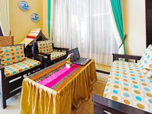 a room with two beds and a table and chairs at OYO LIFE 91551 Gwen Syariah Homestay in Malang