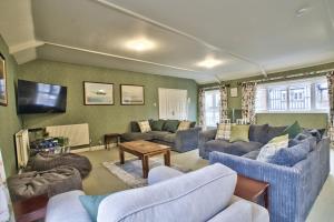 a living room with blue couches and a tv at Fawley Court by Group Retreats in Hereford