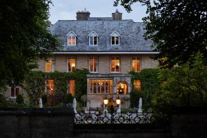 a large house with lights on in front of it at The Slaughters Manor House in Lower Slaughter