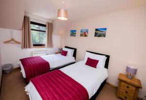 two beds in a bedroom with red and white sheets at The Galleries No 3 in Spean Bridge