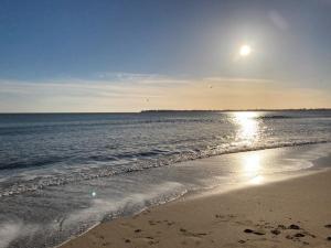 a beach with the sun reflecting on the water at La Capitane in La Baule