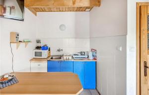 a small kitchen with blue cabinets and a microwave at 2 Bedroom Stunning Home In Sarbinowo in Sarbinowo