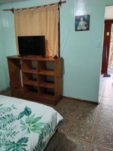 a bedroom with a bed and a desk with a television at Kyea Inn in Hanga Roa