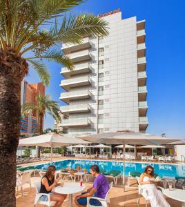 a group of people sitting at tables in front of a hotel at Hotel RH Royal - Adults Only in Benidorm