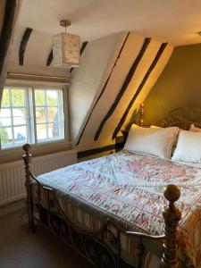 um quarto com uma cama e uma janela em Quirky 18th Century Thatched Cottage em Great Staughton