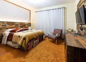 a bedroom with a bed and a flat screen tv at Pousada Kaluana in Urubici