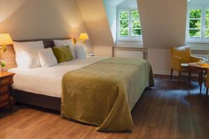 a hotel room with a large bed and two windows at Romantikhotel Altenberger Hof in Odenthal