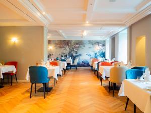 a dining room with white tables and blue chairs at Romantikhotel Altenberger Hof in Odenthal