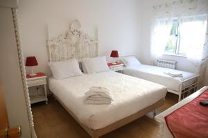 um quarto branco com duas camas e uma janela em Hotel Aviz na Figueira da Foz