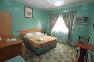 a bedroom with a bed and a window and a desk at Zaineast Hotel in Dubai