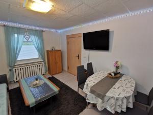 a living room with a table and a flat screen tv at Fewo Krysik Unterdeck in Lühmannsdorf