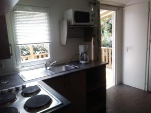 Una cocina con estufa, fregadero y ventana. en Novela, en Port-la-Nouvelle