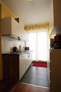 een keuken met witte kasten en een rood tapijt bij Studio-Apartment Sven in Bonn