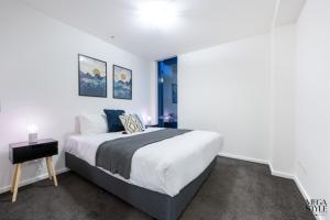 biała sypialnia z łóżkiem i oknem w obiekcie Mega Style Apartments Mainpoint w Melbourne
