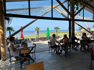 a group of people sitting at tables on the beach at Lake Shkodra Resort in Grilë