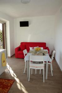 uma sala de estar com uma mesa branca e um sofá vermelho em La Terrazza Del Duca em Marina di Camerota