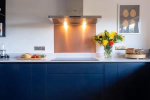 a kitchen with blue cabinets and a vase of flowers at Furzedown Farm House in Hythe