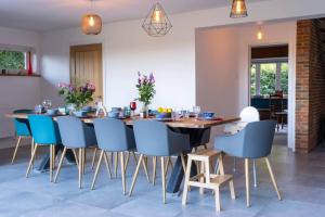 a dining room with a wooden table and blue chairs at Furzedown Farm House in Hythe